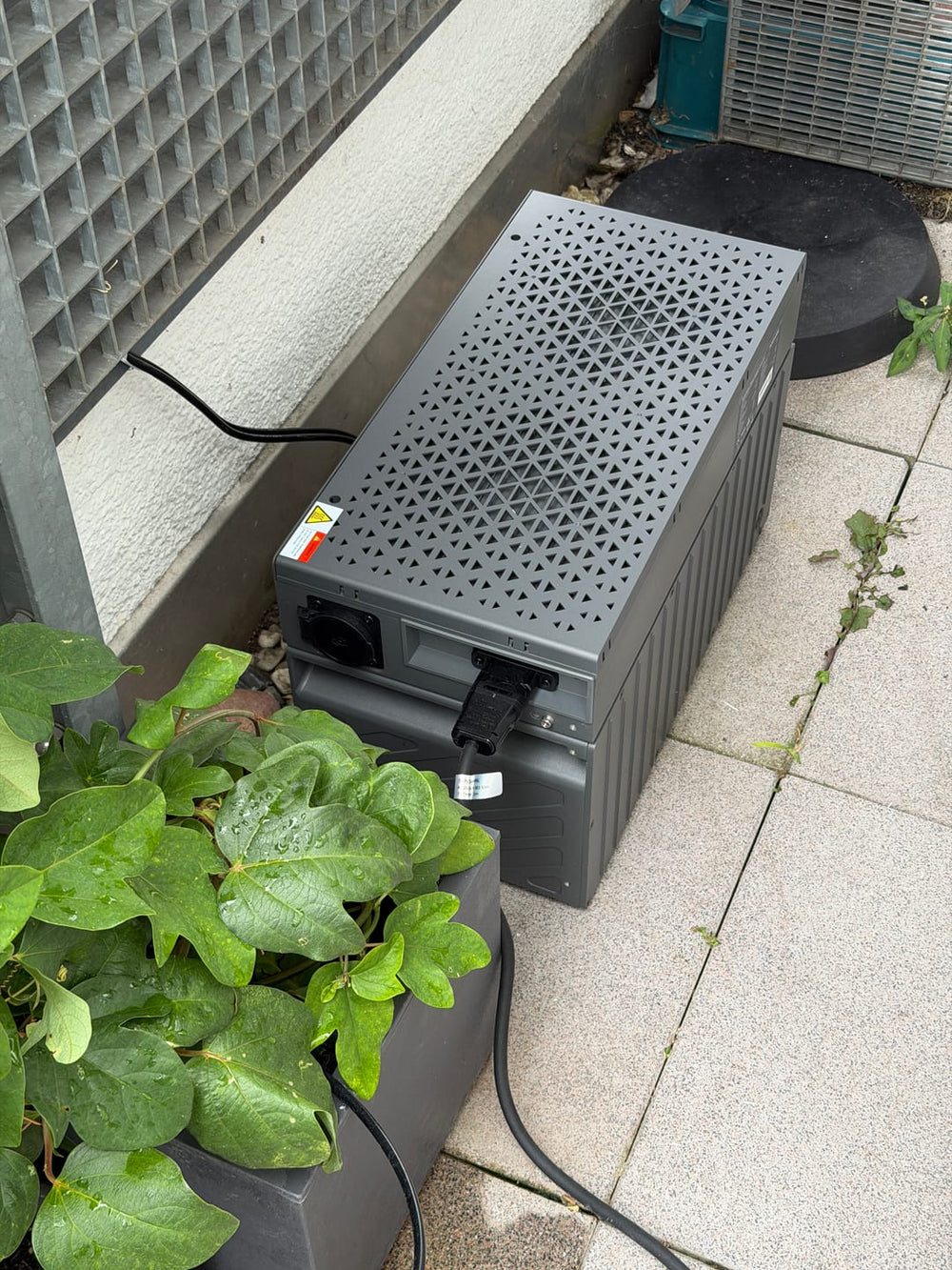 Sunshare Gerät mit angeschlossenen Kabeln auf dem Balkonboden